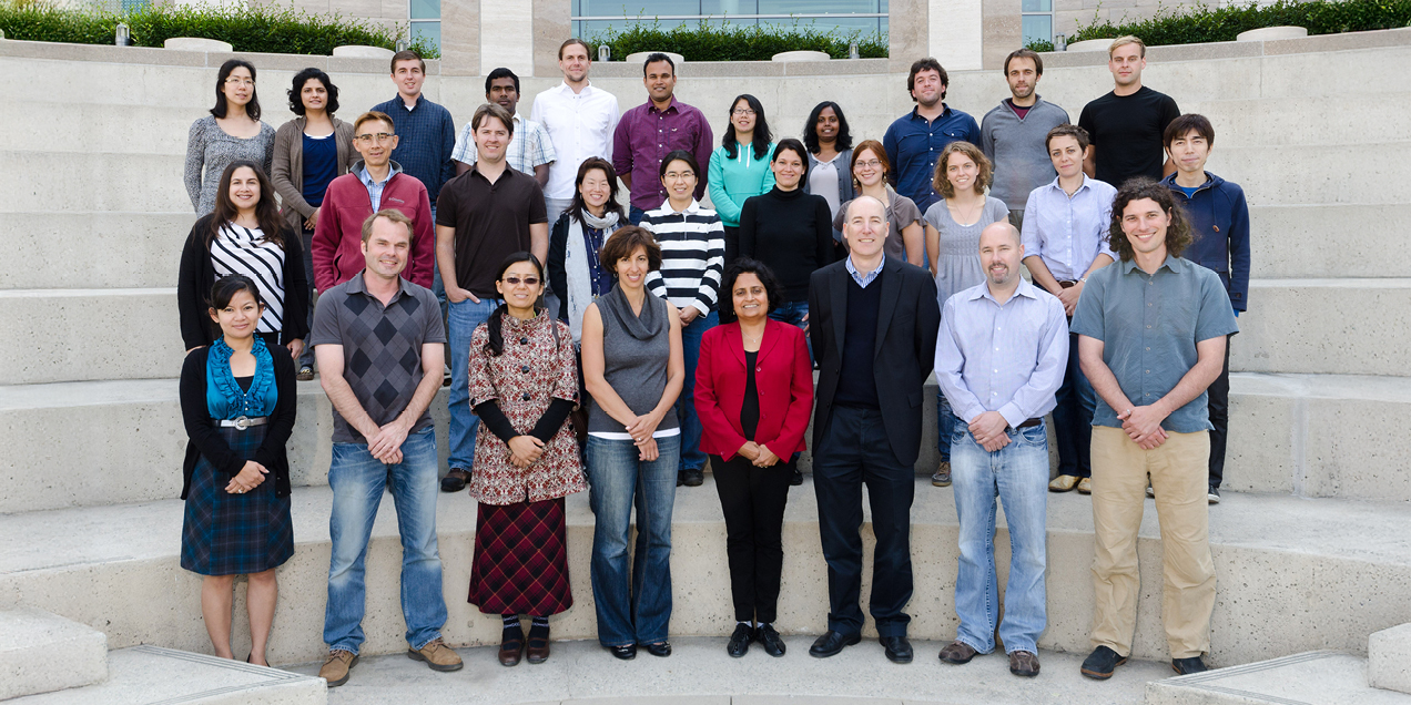 Group of researchers and staff standing together on outdoor concrete steps in front of a campus building.