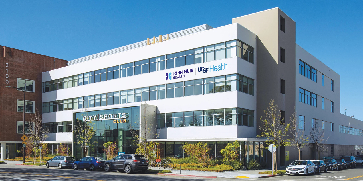 Exterior view of the UCSF China Basin medical building at 185 Berry Street in San Francisco, showing the John Muir Health and UCSF Health signage.