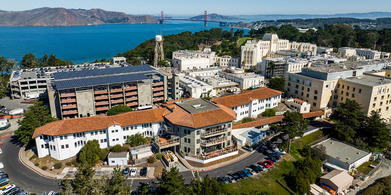 Aerial view of the UCSF Parnassus Heights campus with hospital and research buildings in the foreground and the Golden Gate Bridge and San Francisco Bay in the background.