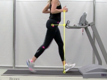Side view of a runner on a treadmill with motion capture markers and a vertical reference line highlighting excessive overstride distance ahead of the body.