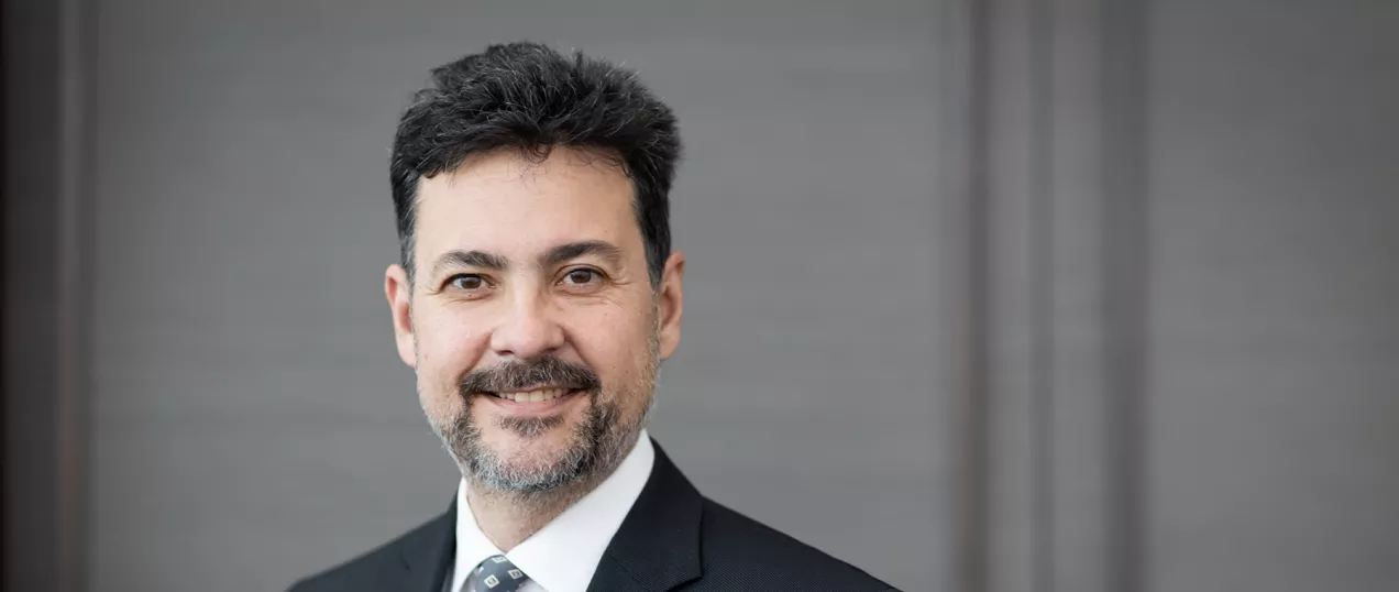 Chair, Christopher Hess headshot of a clinician wearing a suit and tie, smiling toward the camera against a neutral background.