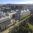 Aerial view of the UCSF Mission Bay campus showing modern research buildings, glass facades, landscaped walkways, and the surrounding San Francisco neighborhood under clear skies.