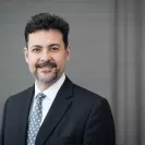 Chair, Christopher Hess headshot of a clinician wearing a suit and tie, smiling toward the camera against a neutral background.