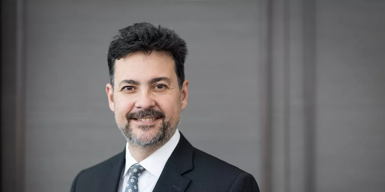 Chair, Christopher Hess headshot of a clinician wearing a suit and tie, smiling toward the camera against a neutral background.