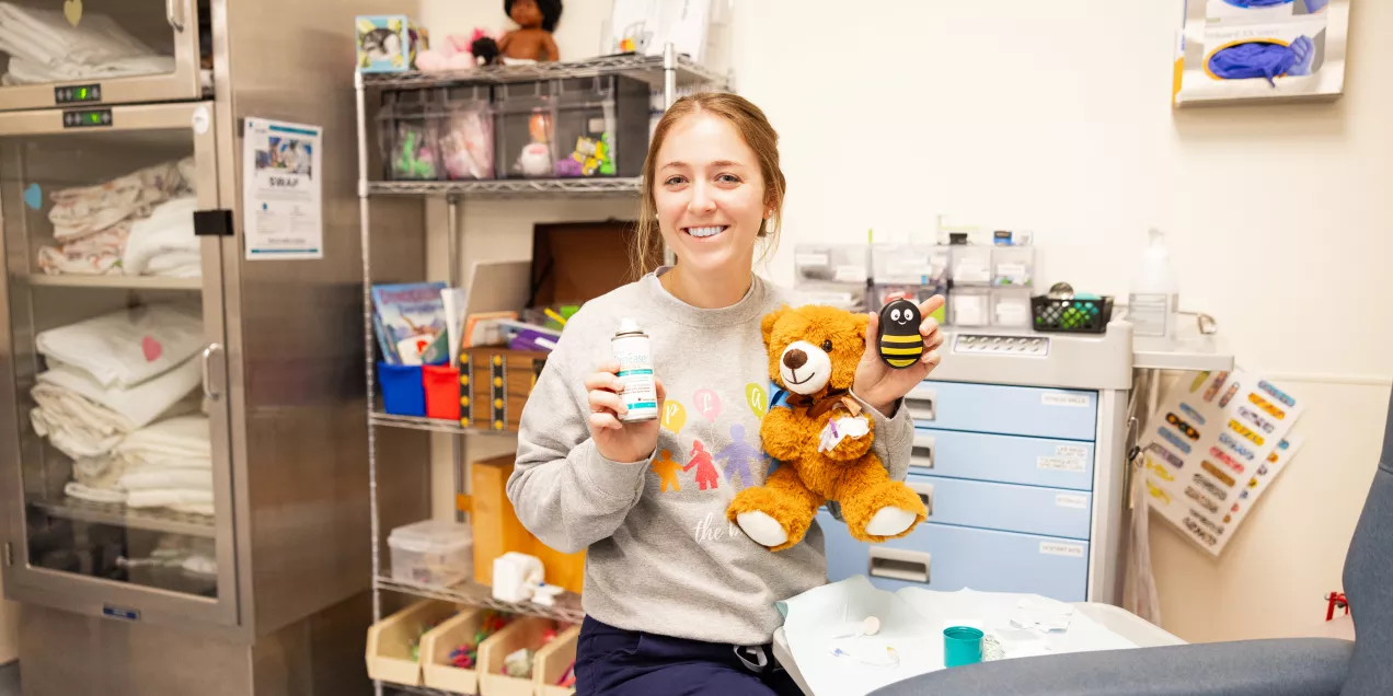 Child life specialist smiling and holding a teddy bear.