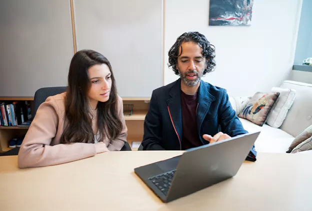 two people sitting in front of a lap top