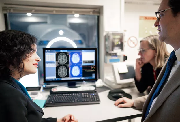 People looking at computer monitor in front of a MRI machine