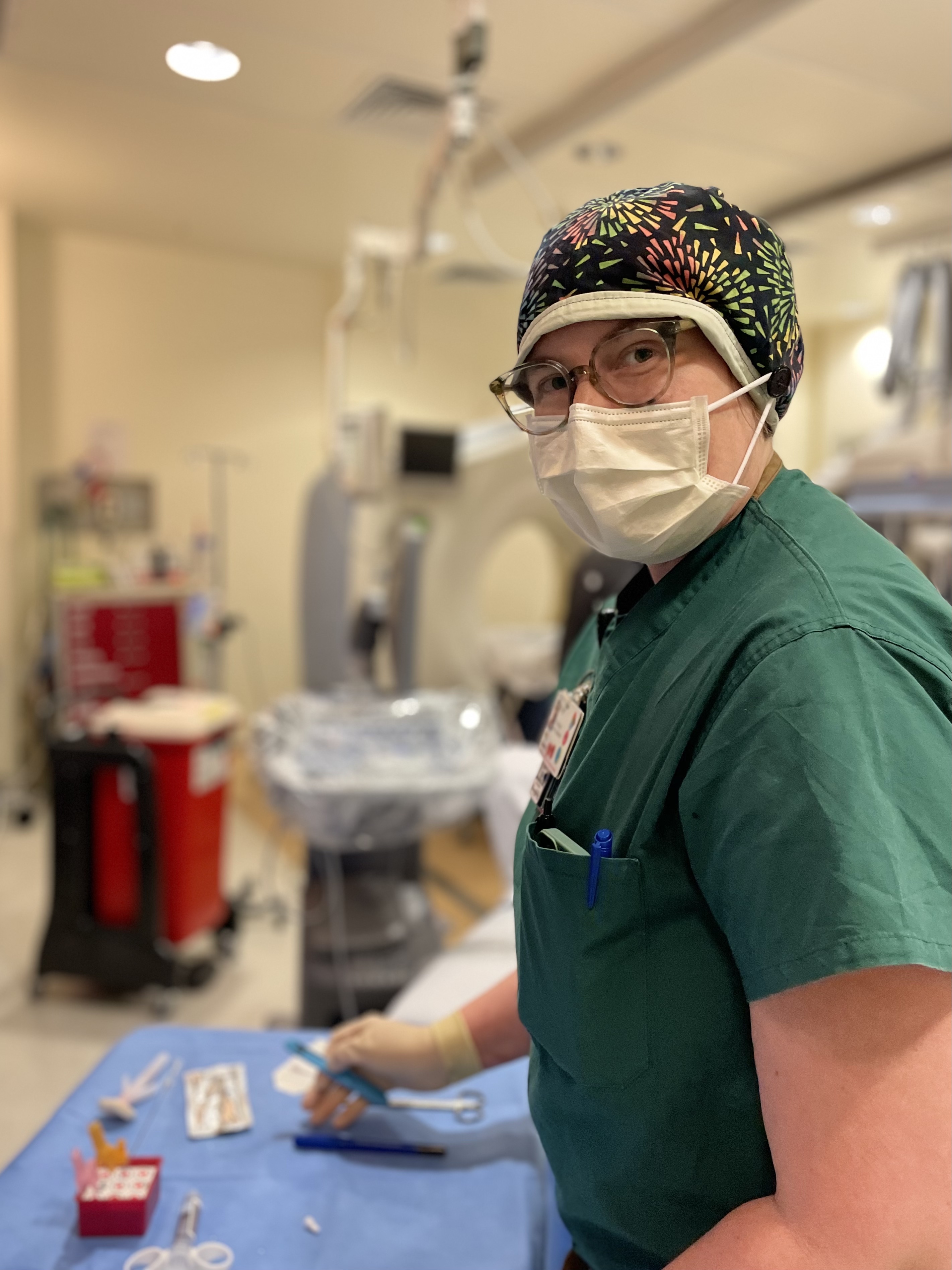 A woman in scrubs in hospital room.