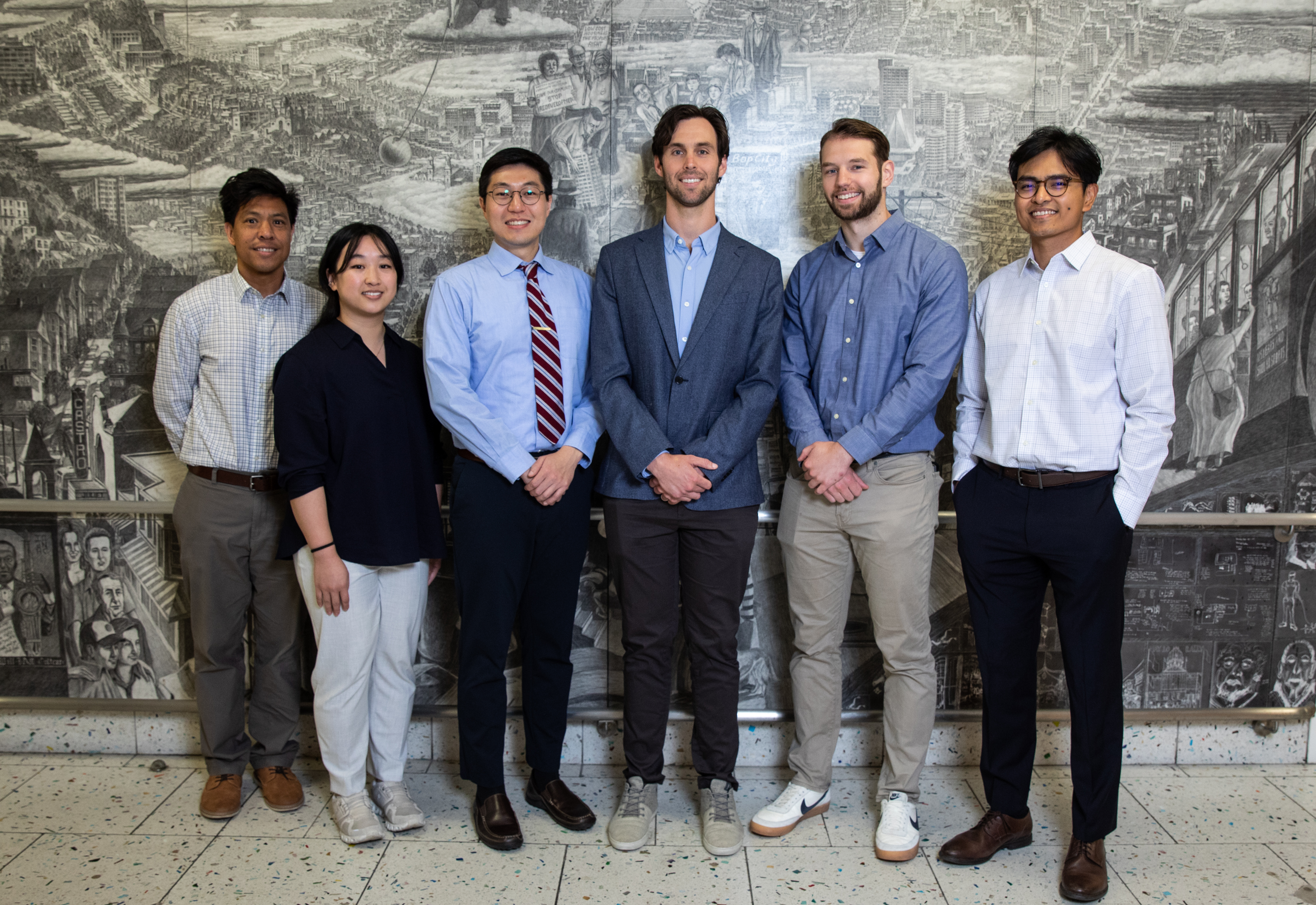 Group photo of the Musculoskeletal Fellowship team standing in front of a grayscale mural.