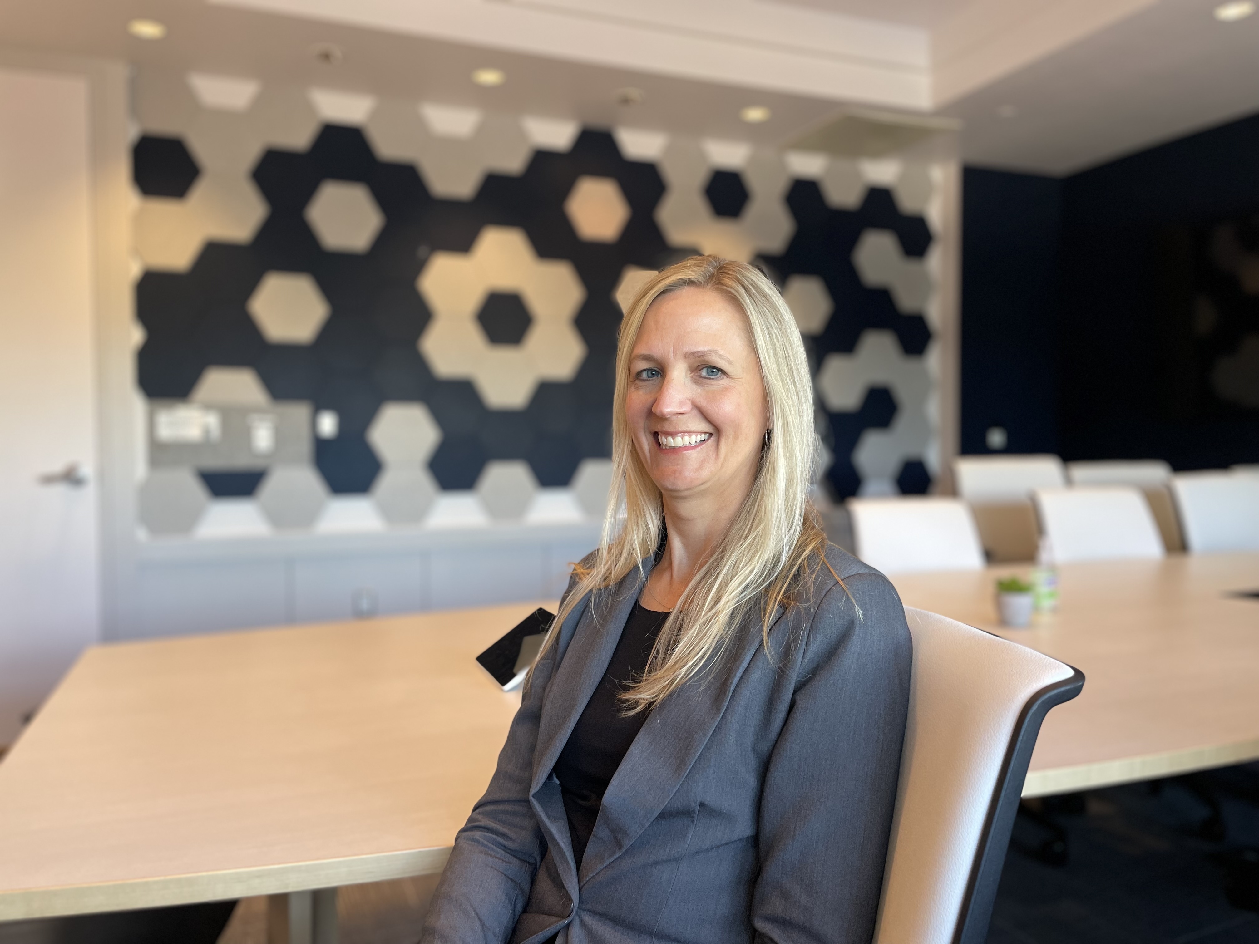 Woman, Jessica Pfannenstiel, sitting in a chair in the Radiology conference room, smiling.