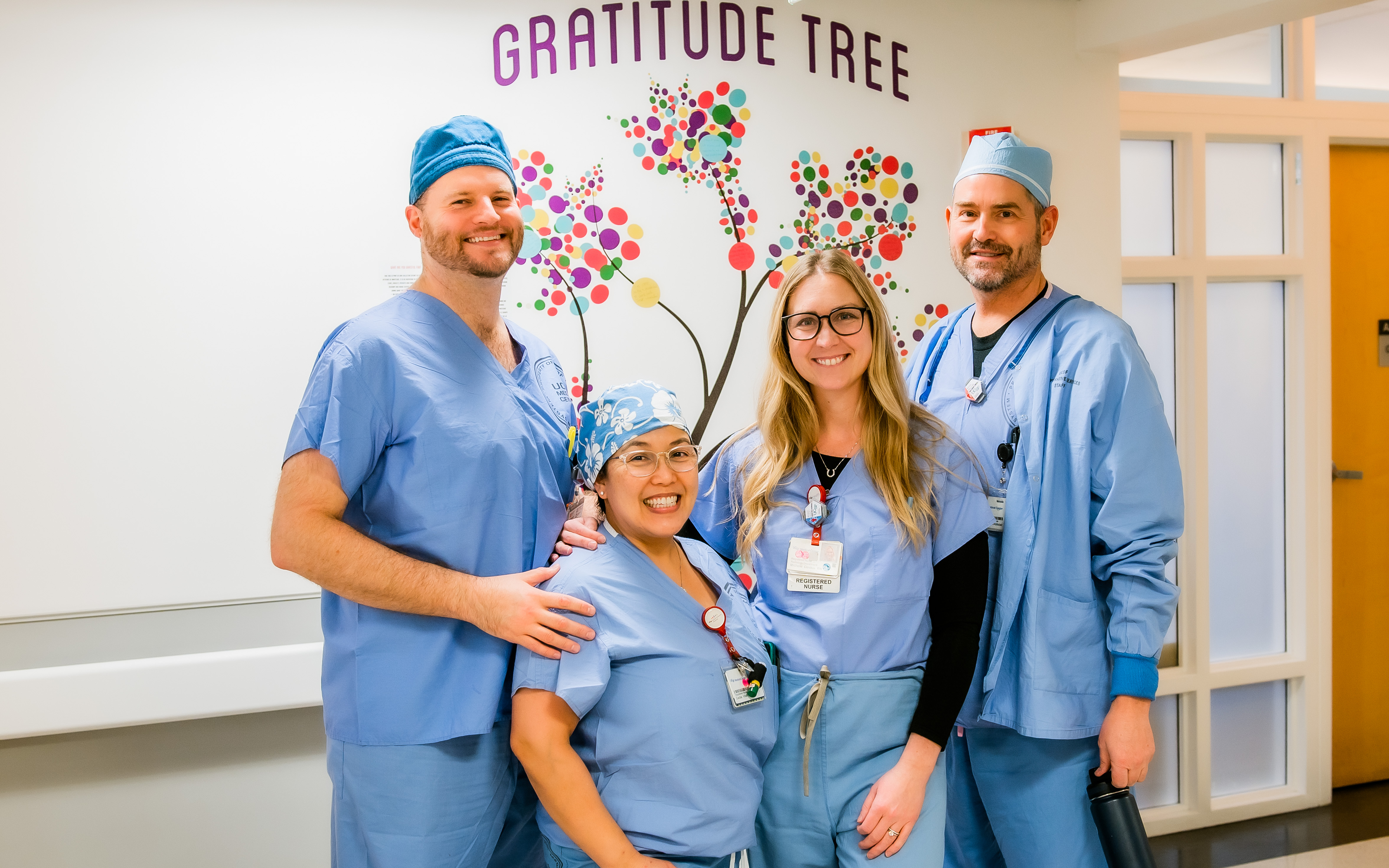 Four people standing in front of a second painted tree