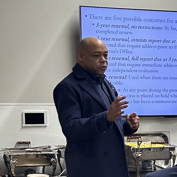 A man in a suit in front of a screen